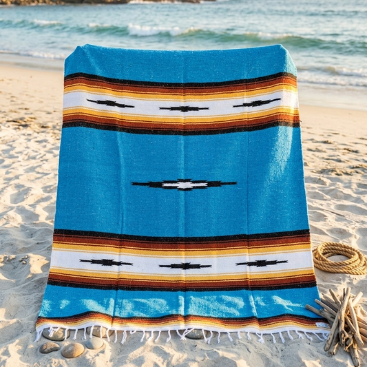 Colorful striped towel on a sandy beach with ocean in the background