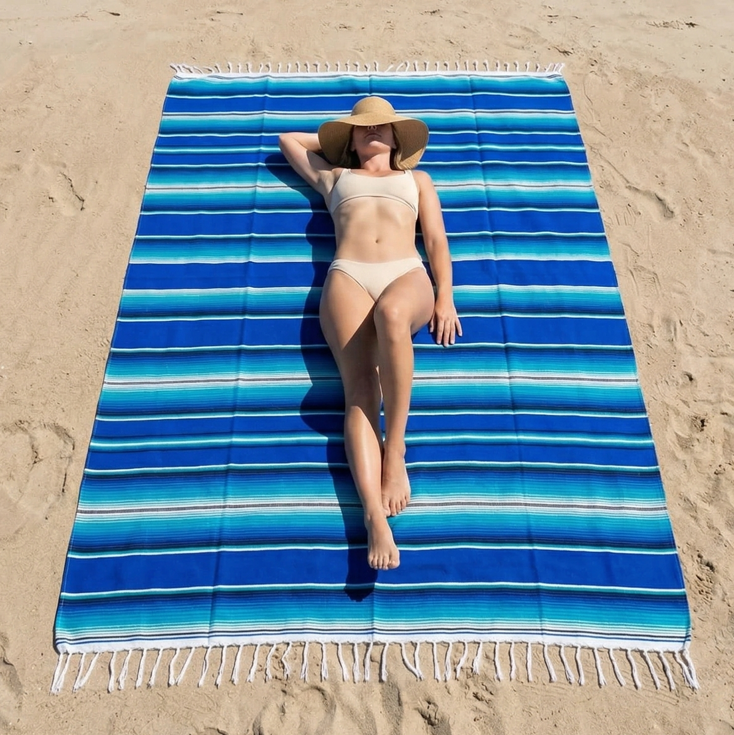 Woman lying on a blue striped beach towel at the beach